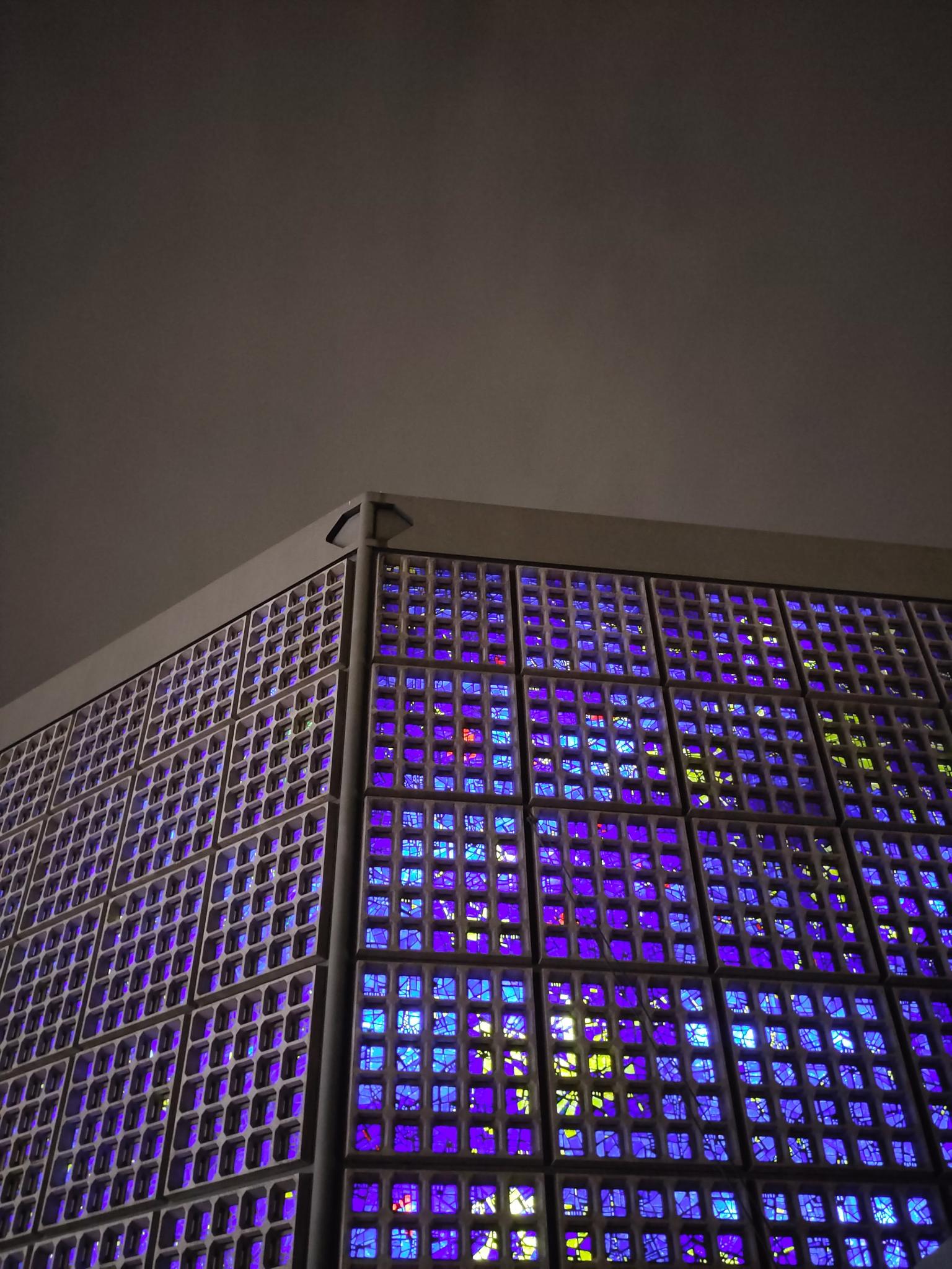 The Gedächnis Kirche in Berkin with its dramatic blue and purple stained glass windows contrasting with grey Berlin sky.