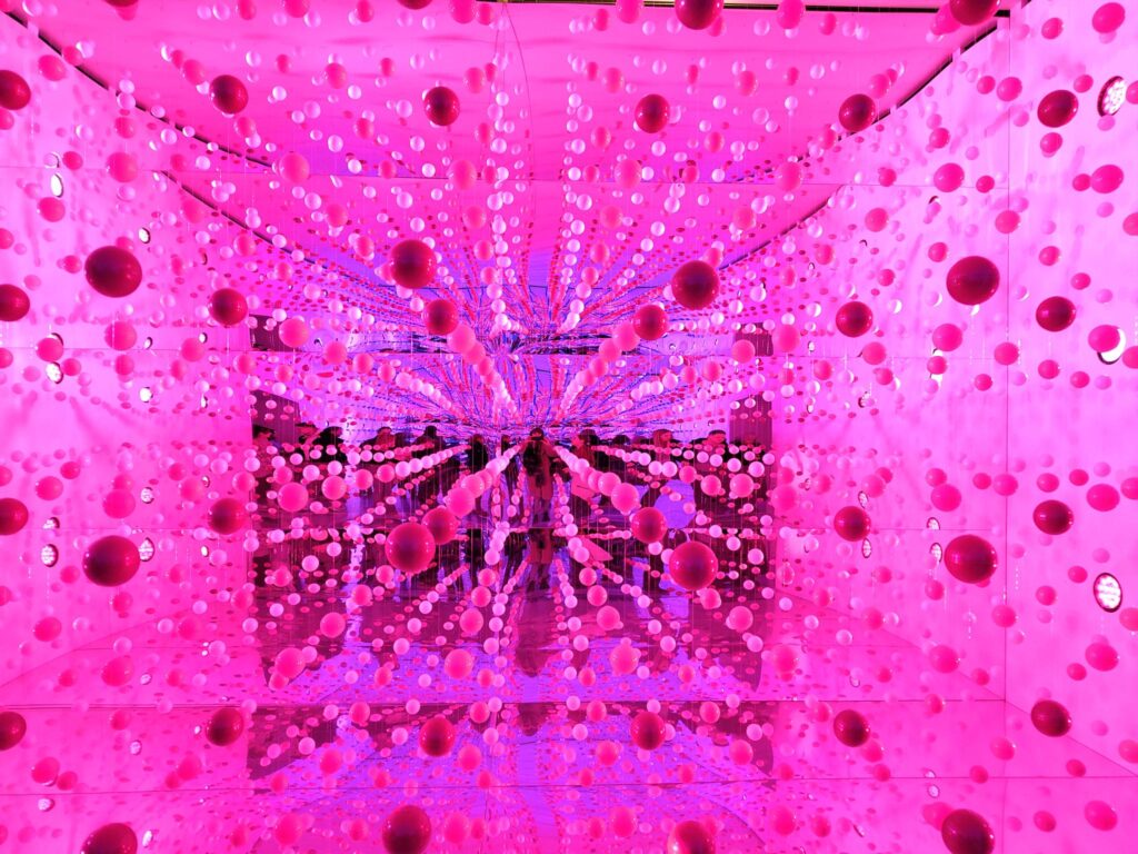 Pink balls illuminated by light at a Berlin exhibition, creating playful and intimate visual effects.