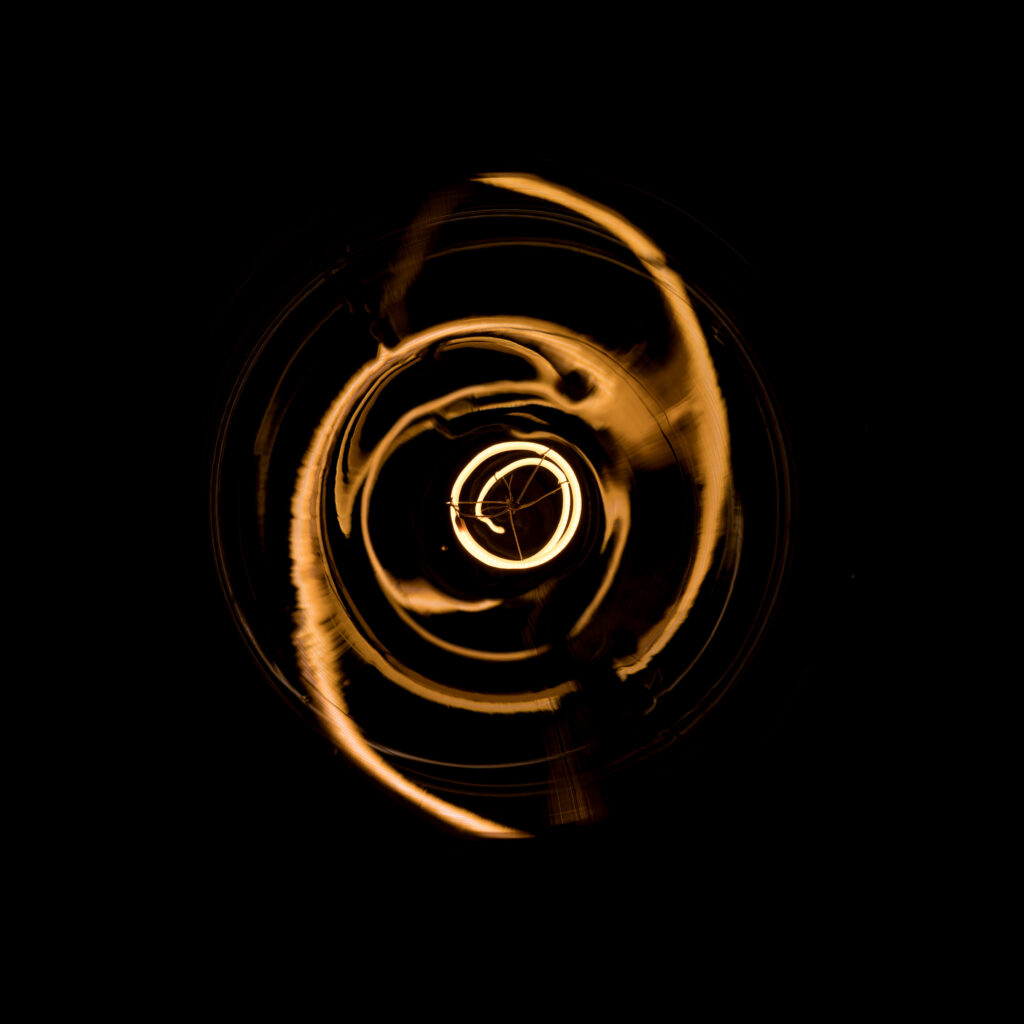 Low-key photograph of a glowing light bulb in Straume, Norway, illustrating atmospheric lighting and sensory design.