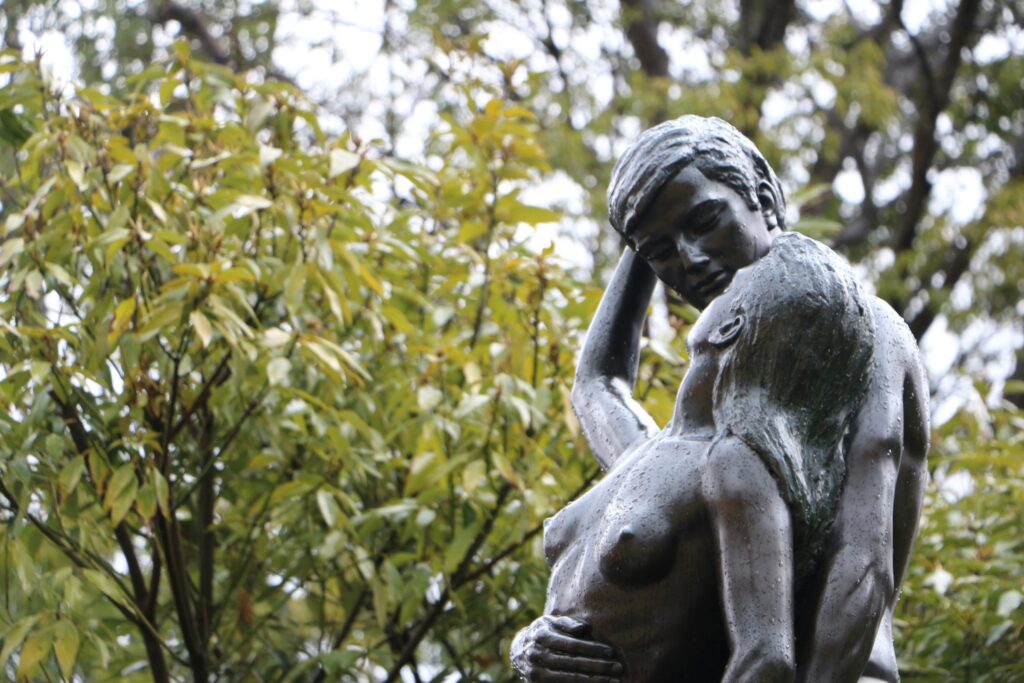 Bronze statue of two lovers in a private embrace.