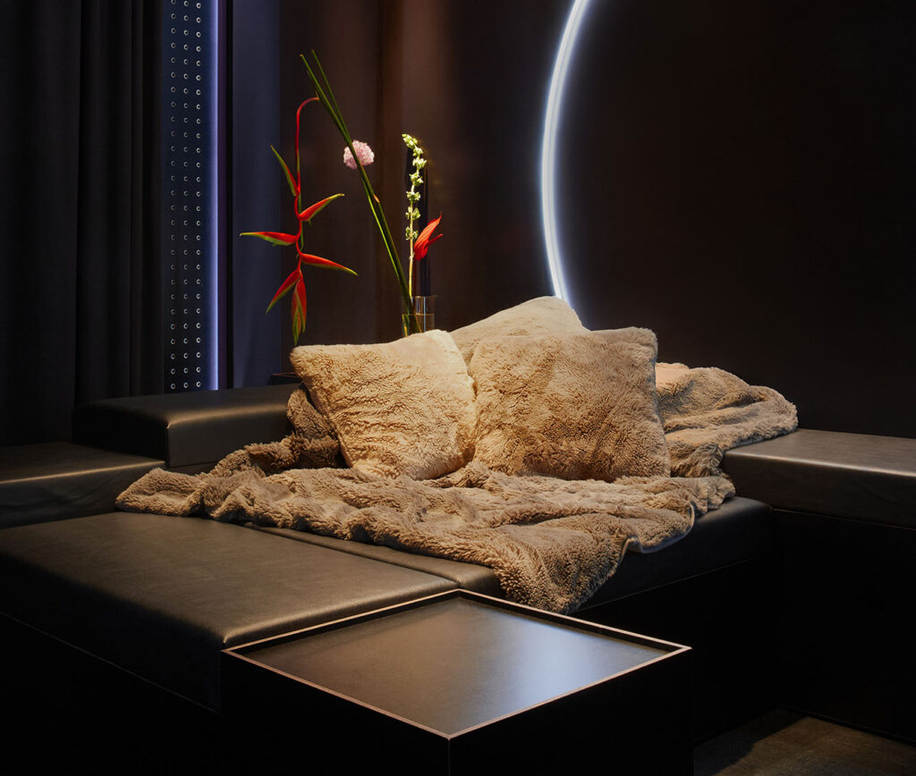 A detailed view of the modular sofa styled with plush luxury rugs and beautiful fresh flowers inside The Circle Berlin private spa retreat.